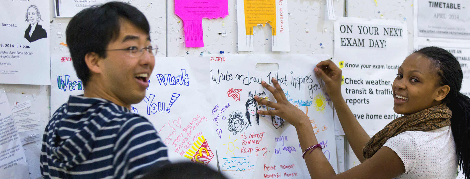 Two students posting reflections on a wall