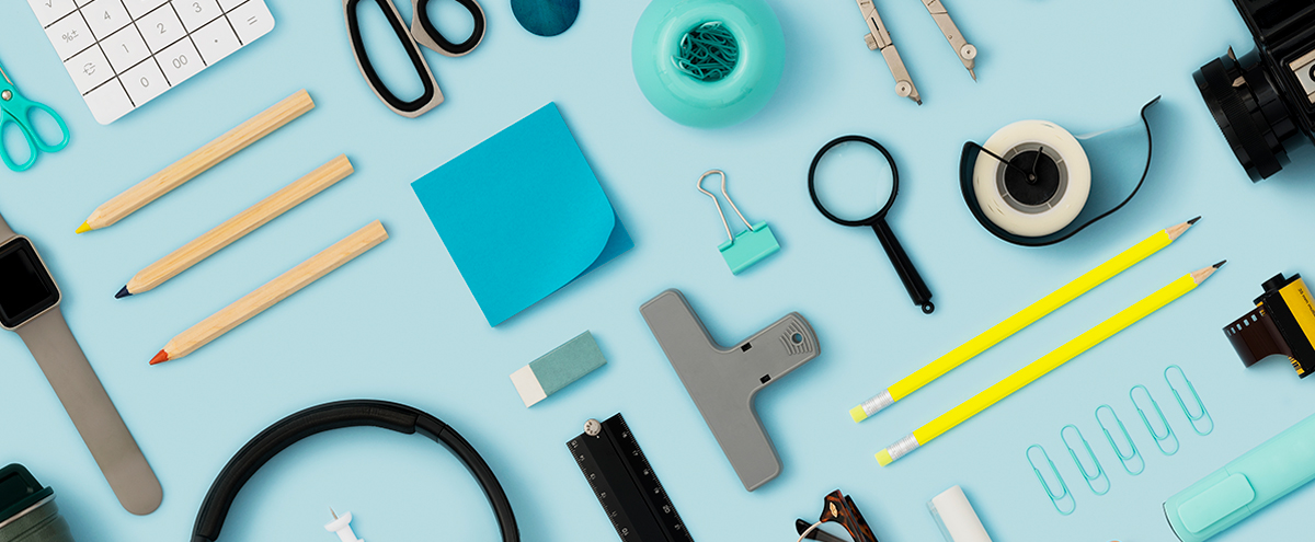 Many different office items are laid out on a table and shot from above.
