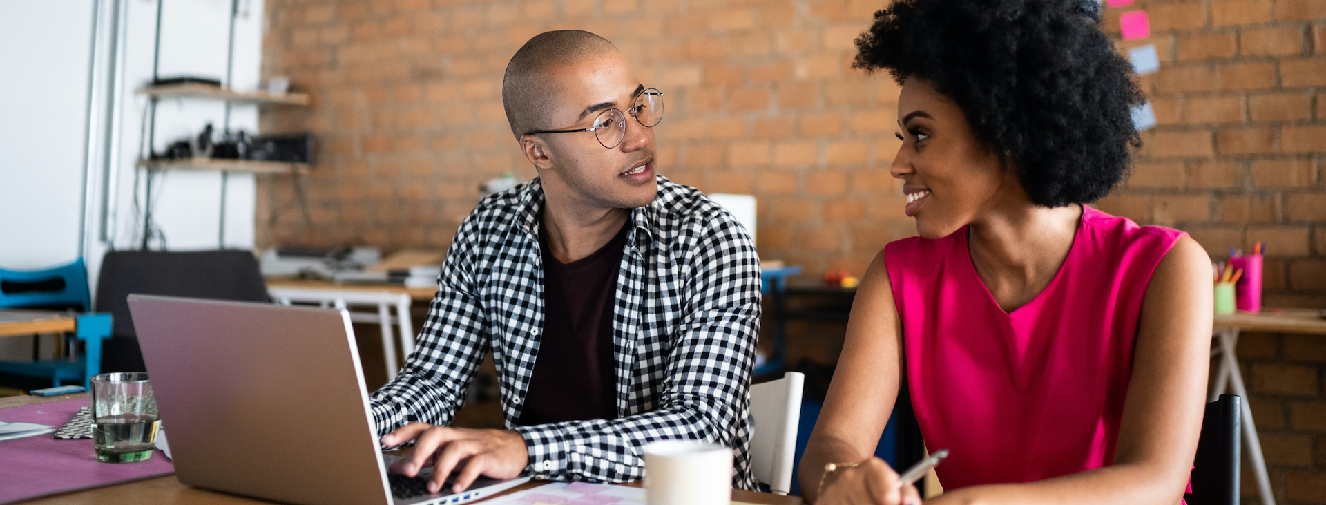 Two colleagues smile at each other over laptop
