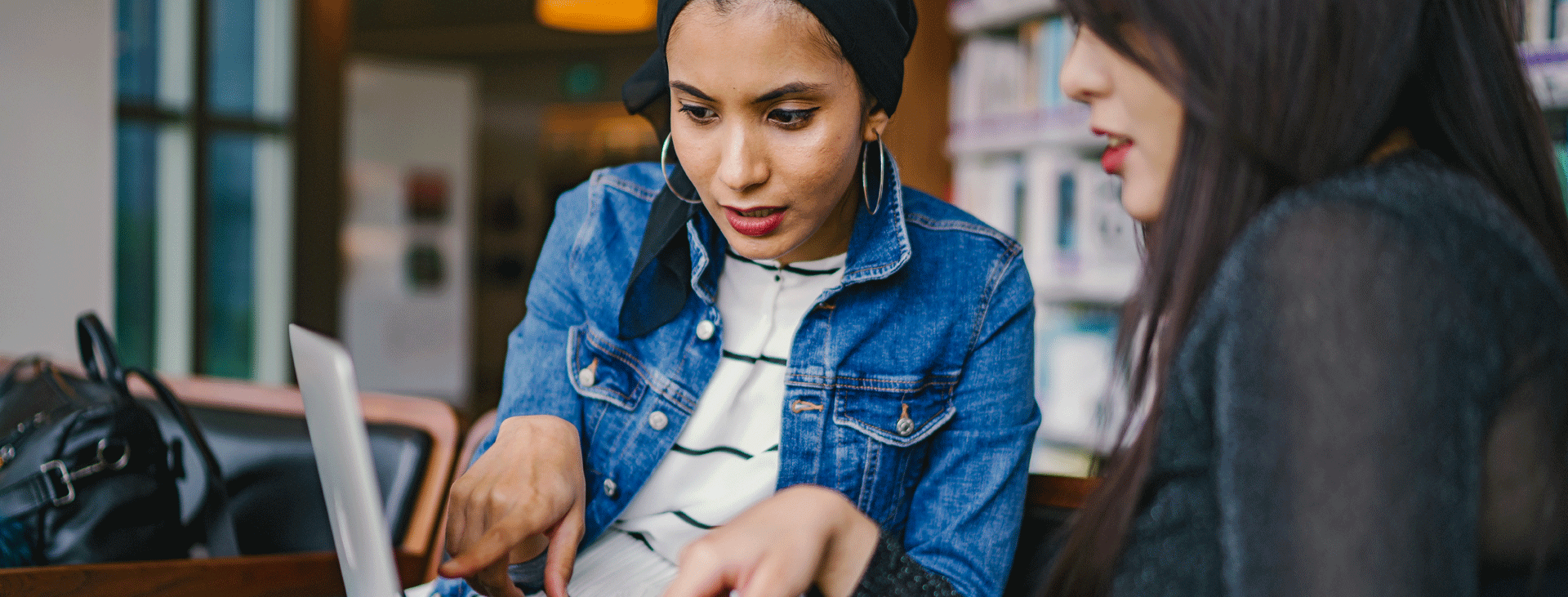 Two yound women looking at a laptop and having a conversation