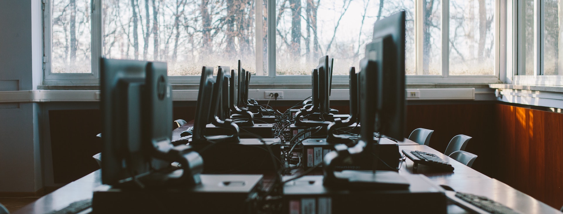 Several desktop computers on a table with windows surrounding it