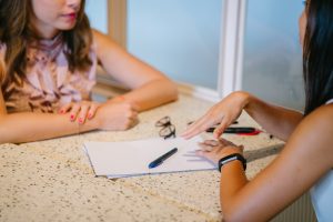 Two women's hands in discussion over papers