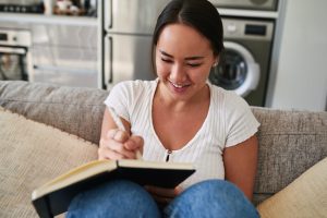 Young woman writing in a notebook while sitting at home