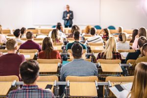 Rear view of large group of students to class in a lecture hall